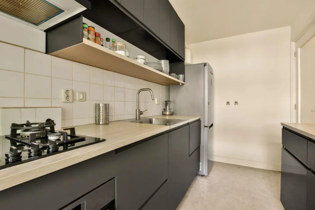 cocina moderna reformada en color negro y beige con suelo de microcemento