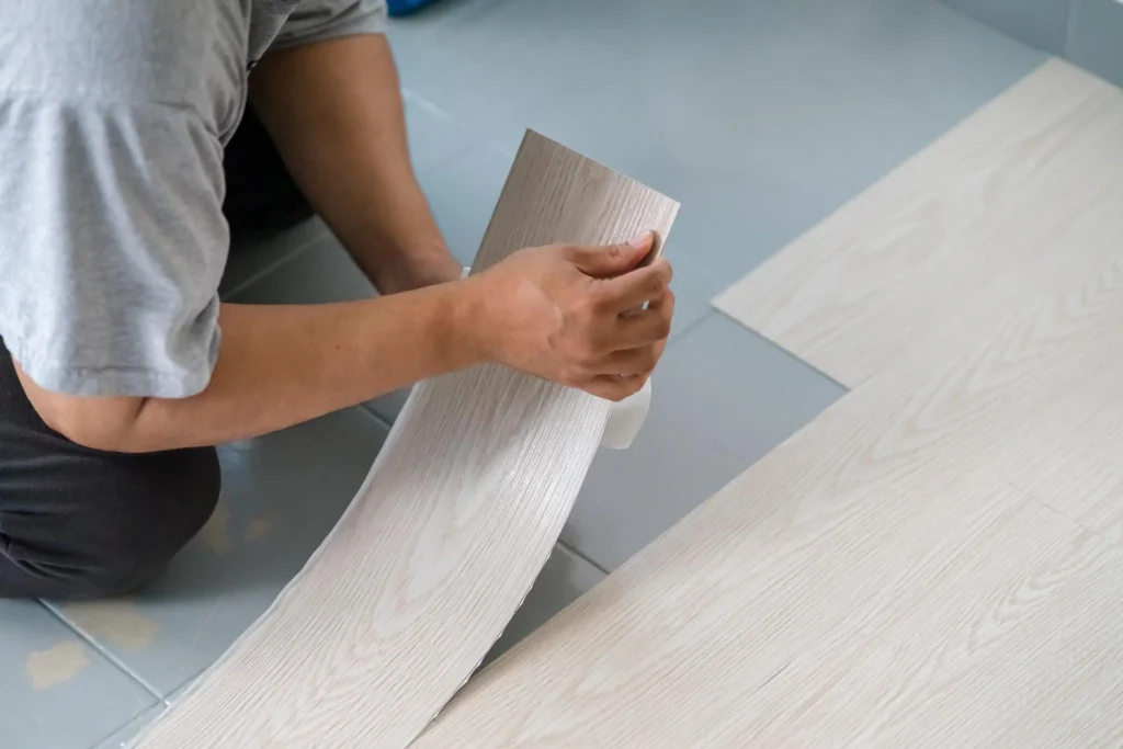Colocación manual de lama de suelo vinílico flexible con acabado efecto madera sobre pavimento interior