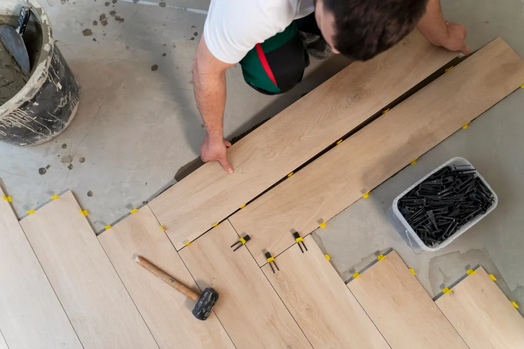 Instalación de suelo laminado imitación madera con cuñas de nivelación y martillo de goma para sistema de suelo radiante