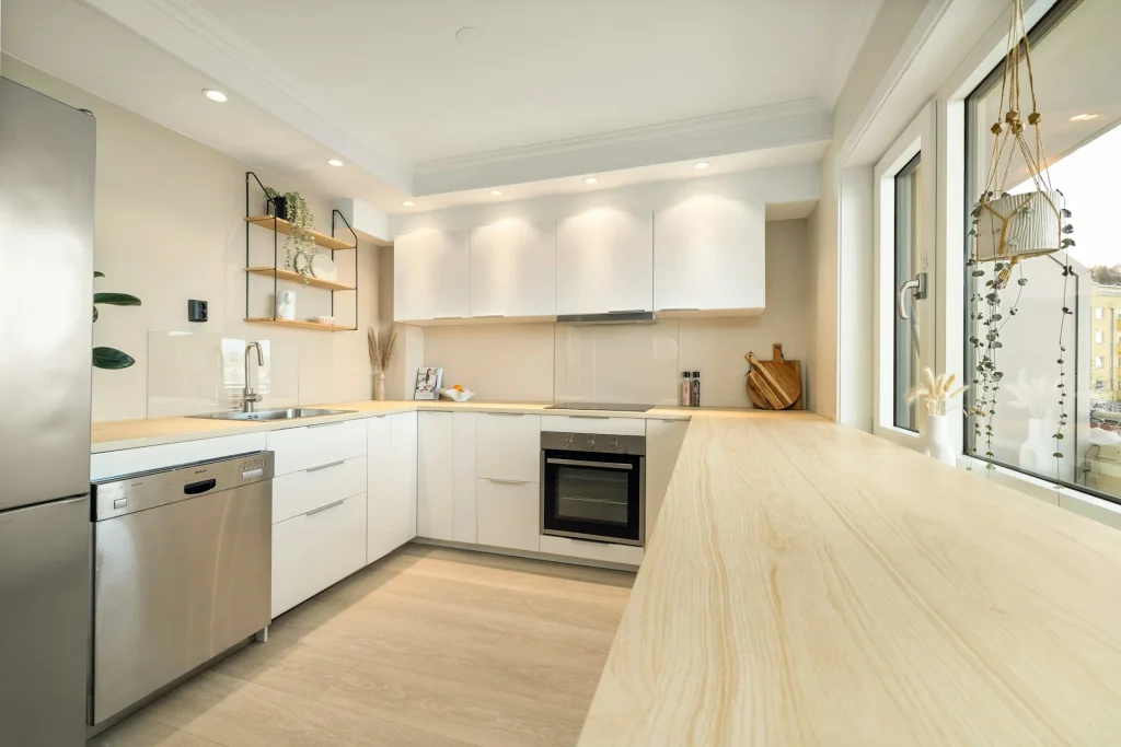 cocina en u con encimera de madera maciza, muebles blancos y detalles en acero inoxidable y negro 